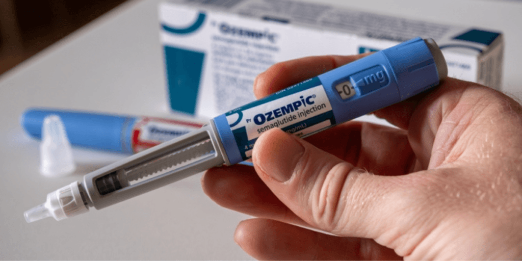 A hand holding an Ozempic injection pen