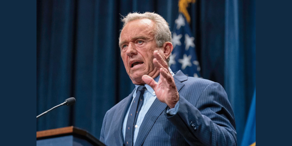 HHS Secretary Robert F. Kennedy Jr. stands at a podium in Washington, D.C., announcing the FDA’s artificial dye ban, with a backdrop featuring the FDA logo and a chart of banned food dyes.